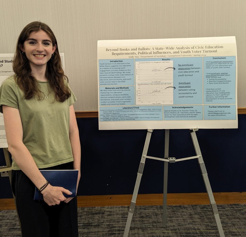 CERL Research Assistant and Georgetown University undergraduate Molly May stands before her Senior Thesis presentation poster.