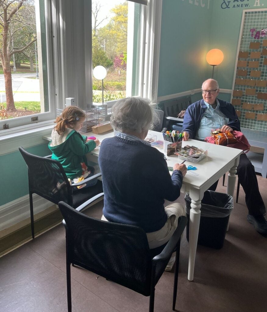 Two senior citizens and a young girl create postcards at Lincoln's Cottage Visitor Center.